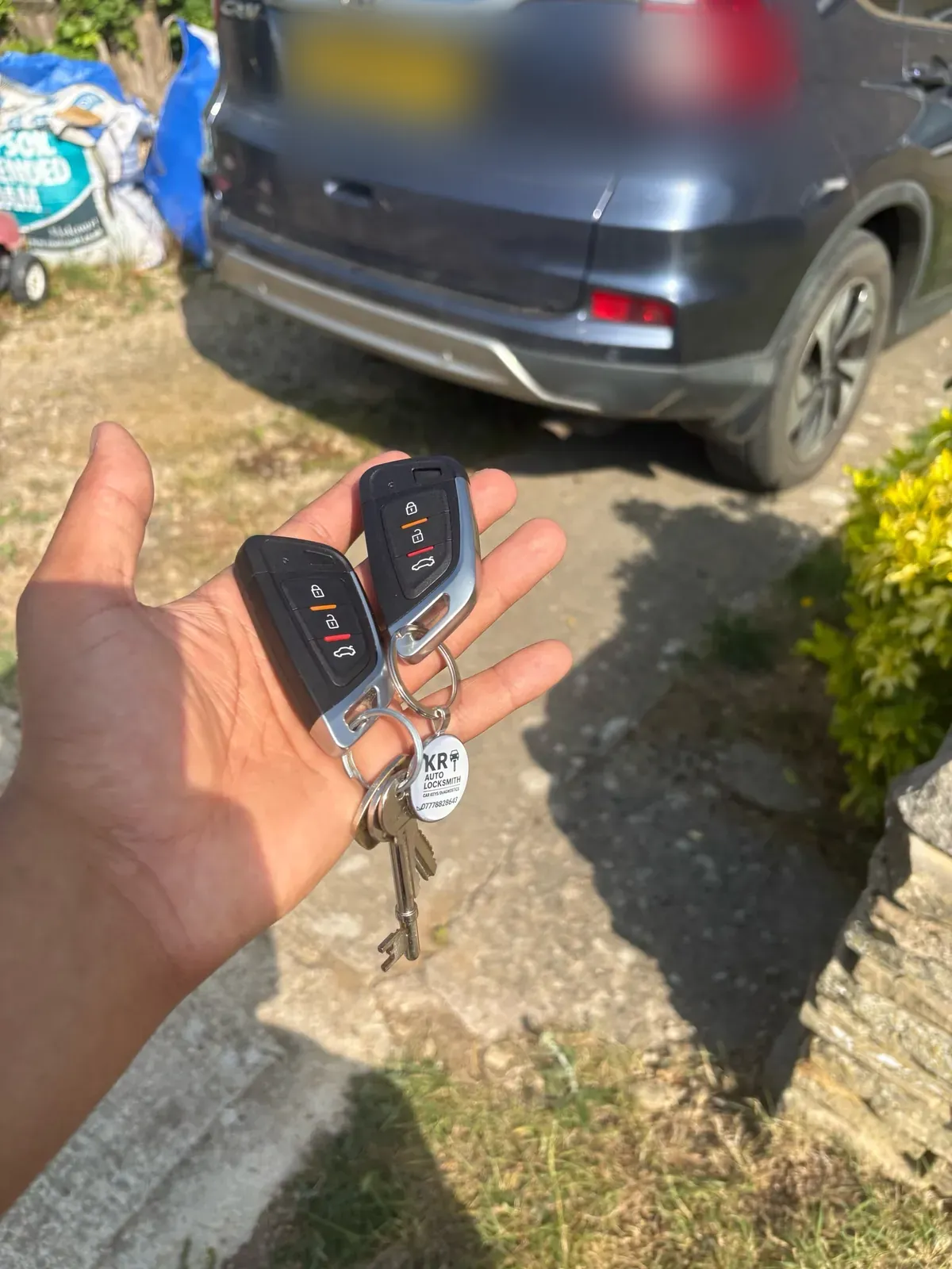 Two programmed keys for a Honda CR-V held in front of the car