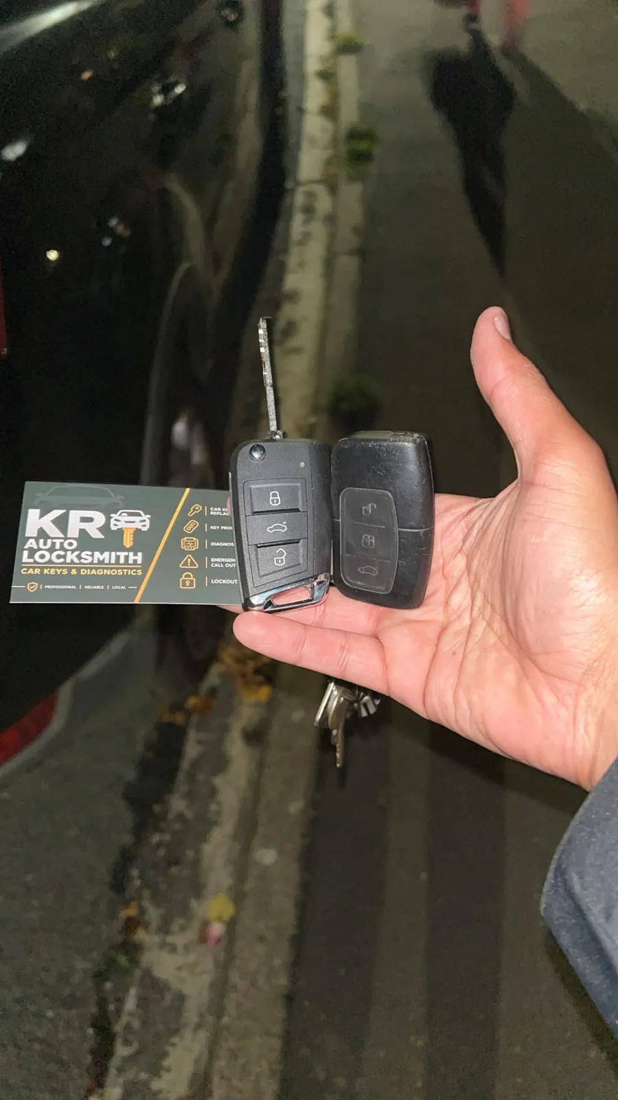 A cut VW flip key and a Ford remote fob held side by side on a dark street, a night call out